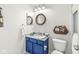 Bathroom featuring blue vanity, round mirror, toilet, light fixtures and white walls at 10143 Winslow Way, Fishers, IN 46037