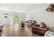 Bright living room with hardwood floors, sliding glass doors to the outside, and a comfortable leather sofa and chair set at 10143 Winslow Way, Fishers, IN 46037