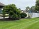 Grassy pool area bordered by a white fence and trees with a glimpse of nearby home exteriors at 10143 Winslow Way, Fishers, IN 46037