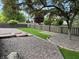 View of the backyard with a green lawn, wooden fence, and stone ground cover, shaded by a large tree at 10305 Lakeland Dr, Fishers, IN 46037