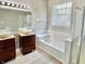 Bright bathroom featuring double vanity sinks, soaking tub, and glass-enclosed shower at 10305 Lakeland Dr, Fishers, IN 46037