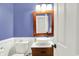 Charming half-bathroom with blue walls, white wainscoting, modern sink, and rustic wood-framed mirror at 10310 Foxwood W Dr, Carmel, IN 46280