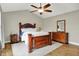 Spacious primary bedroom features wood furniture, a ceiling fan, and ample natural light from the windows at 10310 Foxwood W Dr, Carmel, IN 46280