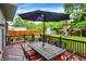 Inviting deck with a table, umbrella, and a backyard view featuring a playset and shed at 10310 Foxwood W Dr, Carmel, IN 46280