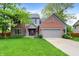 Charming two-story home featuring a well-manicured lawn, brick accents, and an attached two car garage at 10310 Foxwood W Dr, Carmel, IN 46280