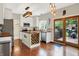Stylish kitchen featuring white cabinets, hardwood floors, an island with wine storage, and a sliding glass door at 10310 Foxwood W Dr, Carmel, IN 46280