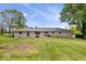 Rear view of stone ranch shows large lawn, mature trees, and manicured yard at 10456 N State Rd 267, Brownsburg, IN 46112