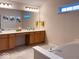 Bright bathroom with dual sinks, a large mirror, and a soaking tub with stylish fixtures at 12253 Bedrock Ct, Fishers, IN 46037