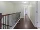 Bright hallway with wood floors, wood handrail, and white trim at 12722 Moonseed Dr, Carmel, IN 46032
