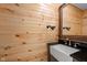 Rustic bathroom with wood paneling, modern sink, and black fixtures, offering a cozy feel at 13765 Howe Rd, Fishers, IN 46038