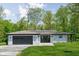 Charming single-story home with a gray garage door, white painted brick and beautifully landscaped front yard at 13765 Howe Rd, Fishers, IN 46038