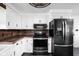 Bright kitchen featuring white cabinets, stainless steel appliances, wood backsplash, and a black oven range at 13765 Howe Rd, Fishers, IN 46038