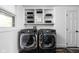 Functional laundry room with modern front load washer and dryer, white cabinets, and ample shelving at 13765 Howe Rd, Fishers, IN 46038