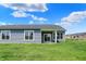 Rear view of home with a covered patio and large windows overlooking the expansive green backyard at 1639 Clover Crossing Dr, Greenfield, IN 46140