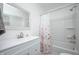 Bright bathroom with white vanity, decorative mirror, and shower with a floral curtain at 1912 Broadway St, Anderson, IN 46012