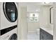 Bright bathroom featuring gray vanity, white marble floors, and a convenient, modern stacked washer and dryer at 1944 Galeston Ct, Indianapolis, IN 46229