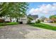 Exterior shot of the house features a gravel driveway, detached garage, and a well-maintained yard at 218 Pearl St, Fortville, IN 46040