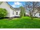 Side exterior view of a well-maintained house with lush green grass and healthy trees at 218 Pearl St, Fortville, IN 46040