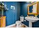 Stylish powder room boasts blue patterned wallpaper, a pedestal sink, and a decorative gold-framed mirror at 3107 Waterfront Cir, Anderson, IN 46012