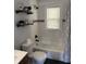 Bright bathroom with a combination shower/tub, updated fixtures, and floating shelves for storage at 3720 W 16Th St, Indianapolis, IN 46222