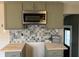 Modern kitchen with painted cabinets, decorative tile backsplash, butcher block countertops, and stainless steel microwave at 3720 W 16Th St, Indianapolis, IN 46222