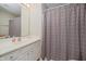 Clean bathroom with a vanity and mirror, next to a shower with patterned curtain at 3743 Earhart Dr, Carmel, IN 46074