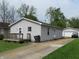 Cozy home with neutral siding, front porch, and long driveway leading to a detached garage at 470 N Pine St, Morgantown, IN 46160