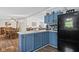 Cozy eat-in kitchen with blue cabinets, black refrigerator, and adjacent dining and living areas at 48 W Adams Brick Ave, Martinsville, IN 46151