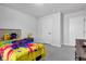 Neutral toned bedroom with grey carpet, view of door and bright yellow and multi-colored bedding at 6305 Norwich Dr, Brownsburg, IN 46112