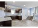 Bright kitchen featuring dark cabinets, a white door, gray countertop, and stairs leading up at 641 E 33Rd St, Indianapolis, IN 46205
