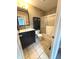 Bathroom featuring tiled walls and floors, black cabinets, and a shower over tub at 6550 Spring Flower Dr, Indianapolis, IN 46237