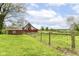 Scenic view of a red barn nestled in a lush green field, enclosed by a rustic fence at 6585 N Waverly Park Rd, Martinsville, IN 46151