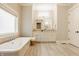 Bright bathroom features a soaking tub, double vanity with white cabinets and light, natural stone flooring at 6734 W Stonegate Dr, Zionsville, IN 46077