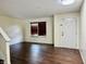 A vacant living room with new wood floors, a window, and white door leading outside at 6903 Governors Pointe Blvd, Indianapolis, IN 46217