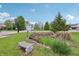 Tranquil front yard featuring a rock garden, decorative bench, lush trees, and green grass at 7157 Chemistry Ct, Indianapolis, IN 46239