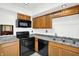Kitchen featuring a black electric range, black microwave, and wooden cabinets at 7642 Lancer Ln, Lawrence, IN 46226