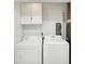 Bright laundry room featuring a full-size washer and dryer with white cabinets above at 7642 Lancer Ln, Lawrence, IN 46226
