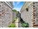 View down a narrow walkway between homes with brick siding, leading to a weathered wooden gate at 7642 Lancer Ln, Lawrence, IN 46226