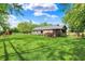 Expansive backyard with lush green lawn, mature trees, wood deck, and partial view of exterior, creating serene outdoor space at 7655 N Kitchen Rd, Mooresville, IN 46158