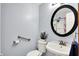 Clean bathroom with a toilet, sink, round mirror, and shower with colorful curtain at 7655 N Kitchen Rd, Mooresville, IN 46158