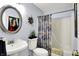 Bathroom with pedestal sink, toilet, shower and bathtub combination, and vibrant floral shower curtain at 7655 N Kitchen Rd, Mooresville, IN 46158