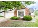 Charming brick home featuring a two-car garage, mature landscaping, and an inviting bay window at 7703 Park North Lake Dr, Indianapolis, IN 46260