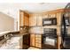 Kitchen features black appliances, wooden cabinets, mosaic backsplash, and tile flooring at 7703 Park North Lake Dr, Indianapolis, IN 46260