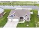 An aerial view of the brick home showing three-car garage, well-kept lawn, and a tranquil pond at 89 Kinnick Dr, Greenwood, IN 46143