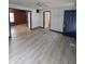Open concept living room with updated flooring, and view to a bedroom and front entry door at 114 S Catherwood Ave, Indianapolis, IN 46219