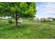 Lush backyard with a mature tree, lawn, wrought iron bench, and a view of a pond at 12739 Kiawah Dr, Carmel, IN 46033