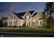 Elegant brick and stone home featuring a manicured lawn, lush landscaping, and a welcoming arched entryway at dusk at 14707 Thor Run Dr, Fishers, IN 46040