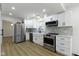 Open kitchen featuring stainless steel appliances, white cabinetry, and stone backsplash at 16 Maplecrest Dr, Carmel, IN 46033