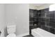 Clean bathroom featuring a modern shower with black tile, a white bathtub, and a toilet at 1610 S F St, Elwood, IN 46036