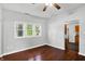 Open living room showcasing dark hardwood floors, neutral walls, multiple windows, and a ceiling fan at 1610 S F St, Elwood, IN 46036
